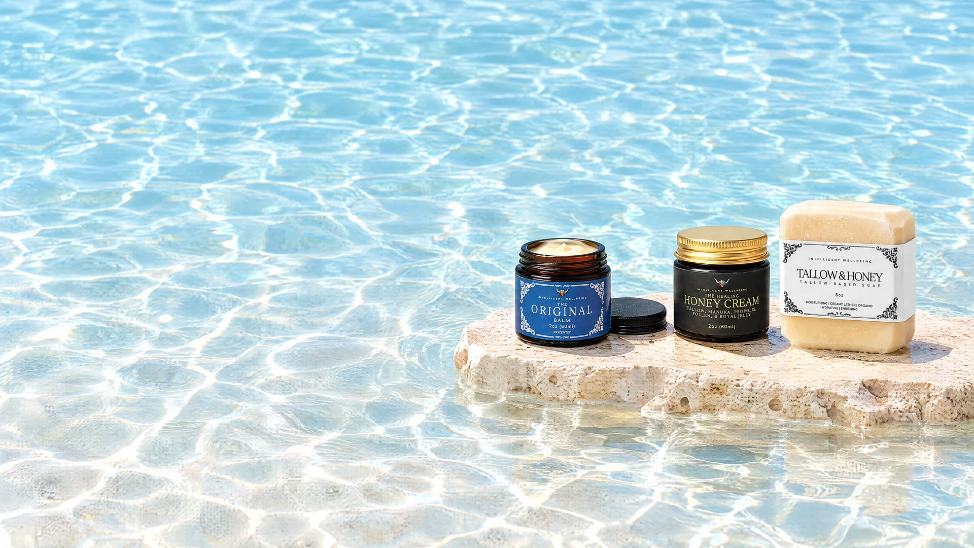The Original Balm, The Healing Honey Cream and a Tallow and Honey soap bar on a stone ledge in sunlit water