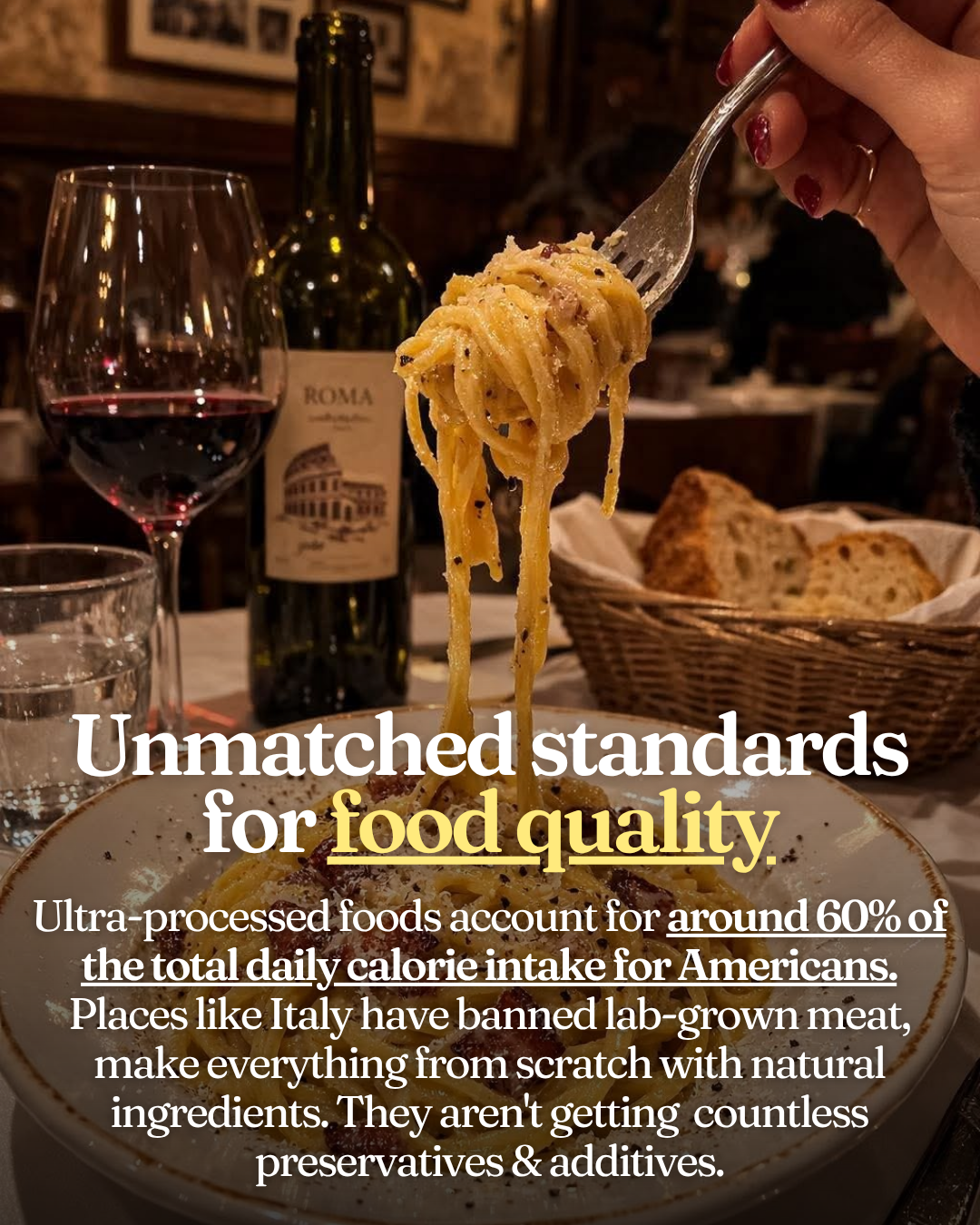 A hand lifting a forkful of spaghetti carbonara from a bowl in a Roman restaurant, with a glass of red wine and a bottle labeled Roma in the background