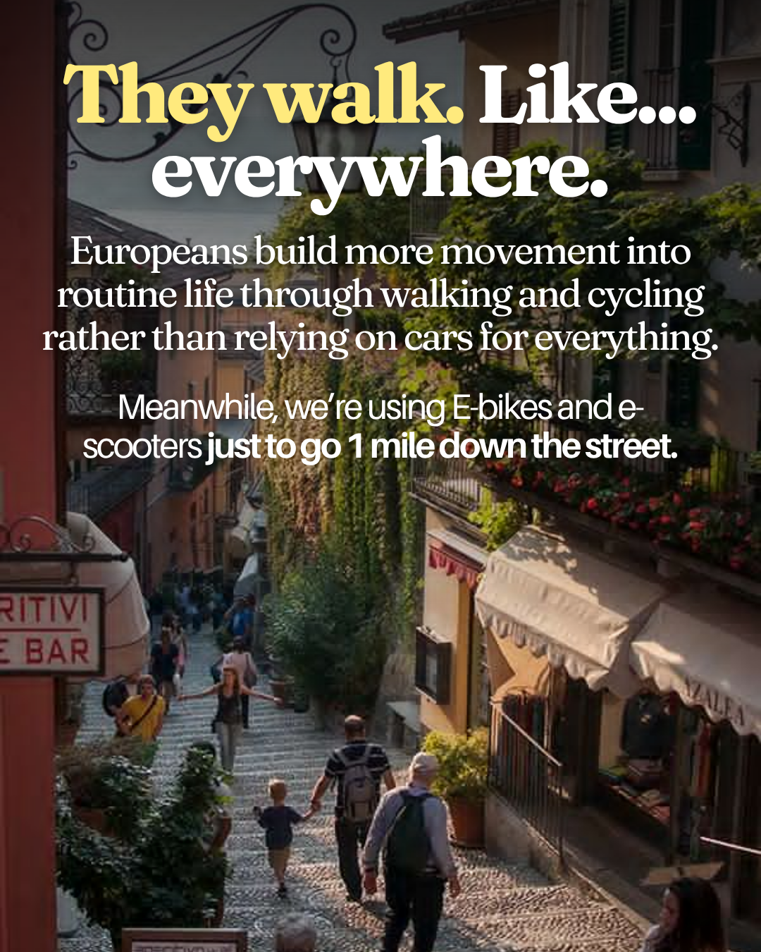 Pedestrians walking up a wide cobblestone stepped street lined with cafes, flower boxes on balconies, and hanging street signs in a charming Italian hill town